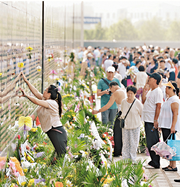 ■市民昨日來到唐山大地震紀念牆前，將鮮花粘貼在遇難親人的名字旁邊表達哀思。新華社