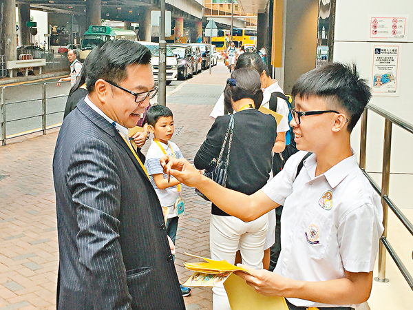 ■東華三院第一副主席李鋈麟（左）向參與東華三院賣旗日活動的學生義工買旗。
