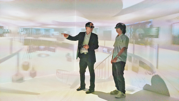 ■黃彥璋（左）模擬利用VR系統教學，投射畫面充滿疊影，師生戴上專用眼鏡觀看3D效果。 吳希雯  攝