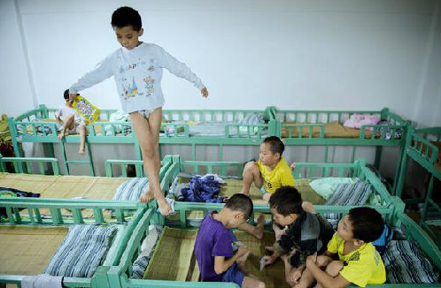 在中國湖南的一個寄宿學校宿舍裡，一個男孩站在床欄上練平衡，其他孩子在打牌。