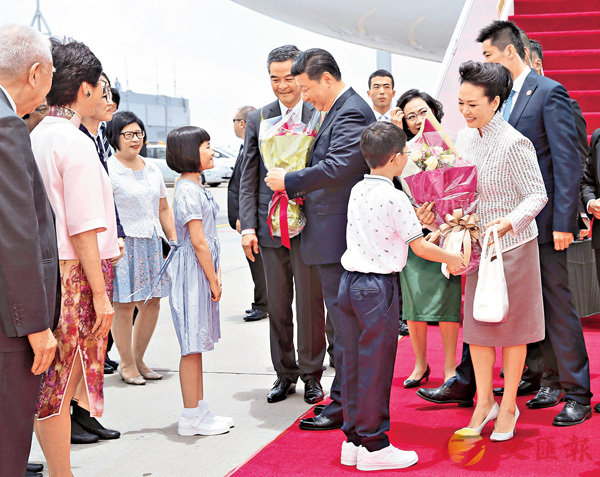 ■習近平主席和夫人彭麗媛在機場接受兩名香港小朋友敬獻鮮花。 新華社