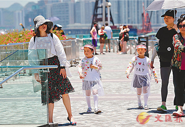 ■訪港遊客穿上防曬服飾在尖沙咀遊覽。  中新社