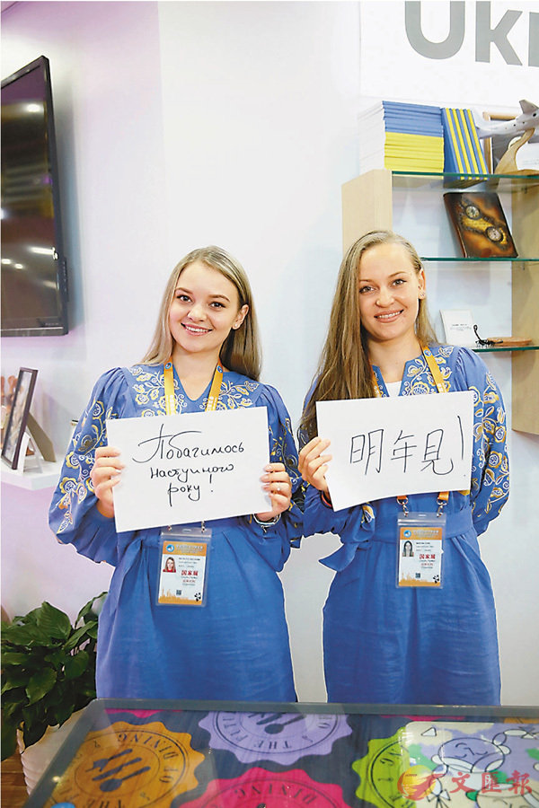 ■烏克蘭展區的工作人員納塔利婭（左）和馬林娜展示烏克蘭語版和中文版的「明年見」。 新華社