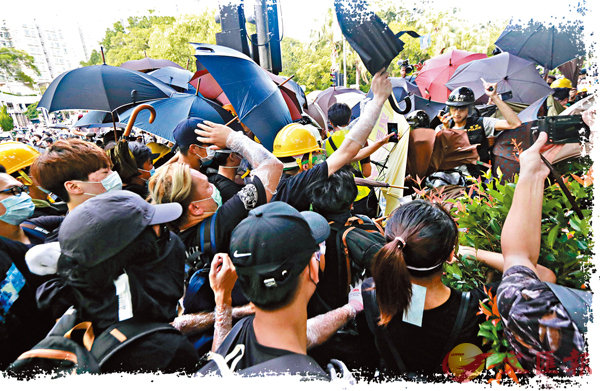 ■大批示威者包圍4名警員，並不斷以雨傘攻擊。 香港文匯報記者  攝