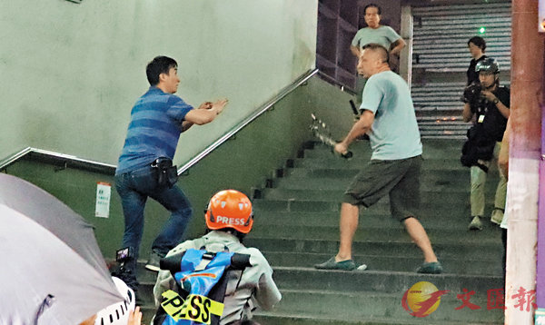 ■ 藍衣男子想上樓梯逃避，有人將他推下樓梯圍毆。 香港文匯報記者 攝