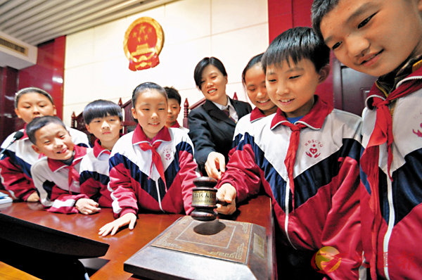 ■習近平表示,要加強制度宣傳教育,特別是要加強對青少年的制度教育。圖為在河北省邯鄲市叢台區人民法院,法官向小學生講解法槌的使用。 資料圖片