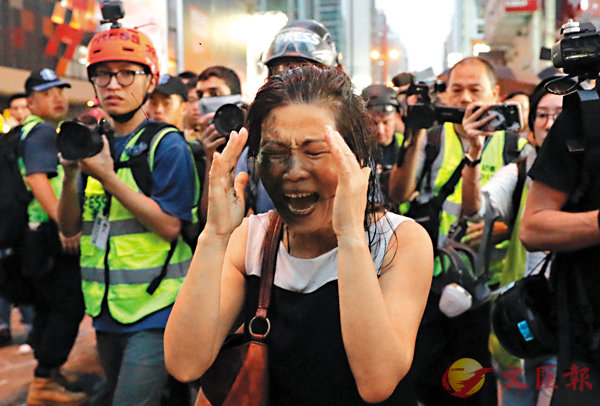 ■ 一名女子在彌敦道近匯豐銀行遭行私刑，面部被噴黑。 美聯社