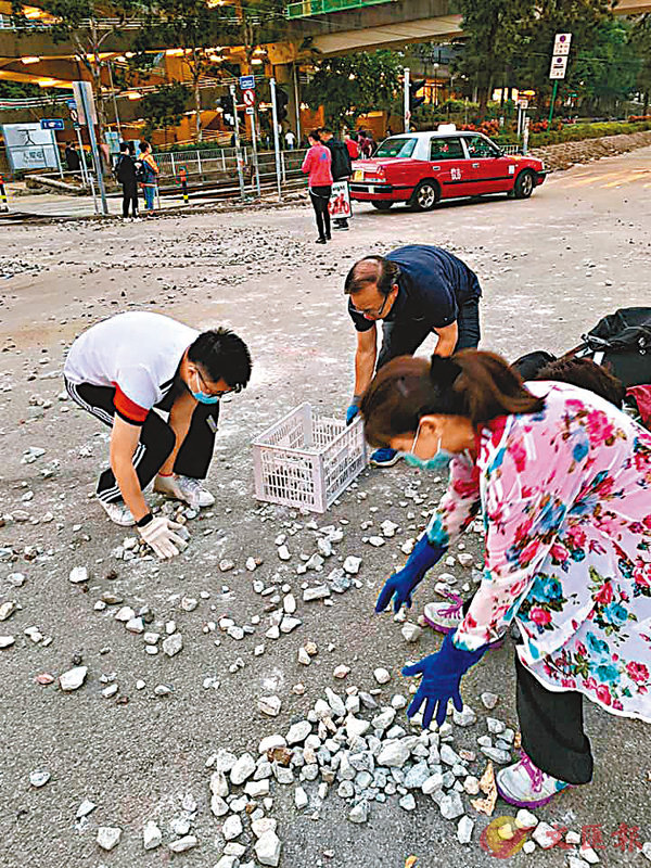 ■梁志祥與街坊一起清理路面碎石。香港文匯報記者 攝
