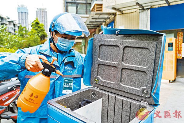 ■ 會議亦要求援助快遞員度過時艱。圖為四川一位外賣員為餐箱消毒。 新華社