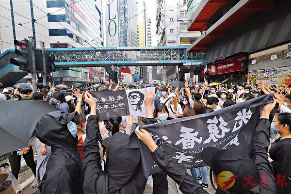 ■ 有人高舉「光復香港，時代革命」標語及梁天琦的肖像。香港文匯報記者  攝