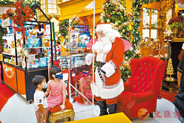 ■ 馬來西亞一個商場內，聖誕老人戴上面罩與小朋友見面。美聯社