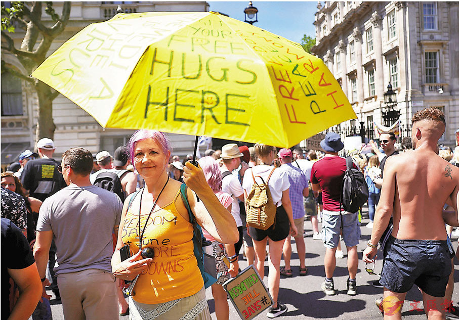 ● 英國反封城示威者舉起寫有「免費擁抱」字樣的雨傘。 路透社